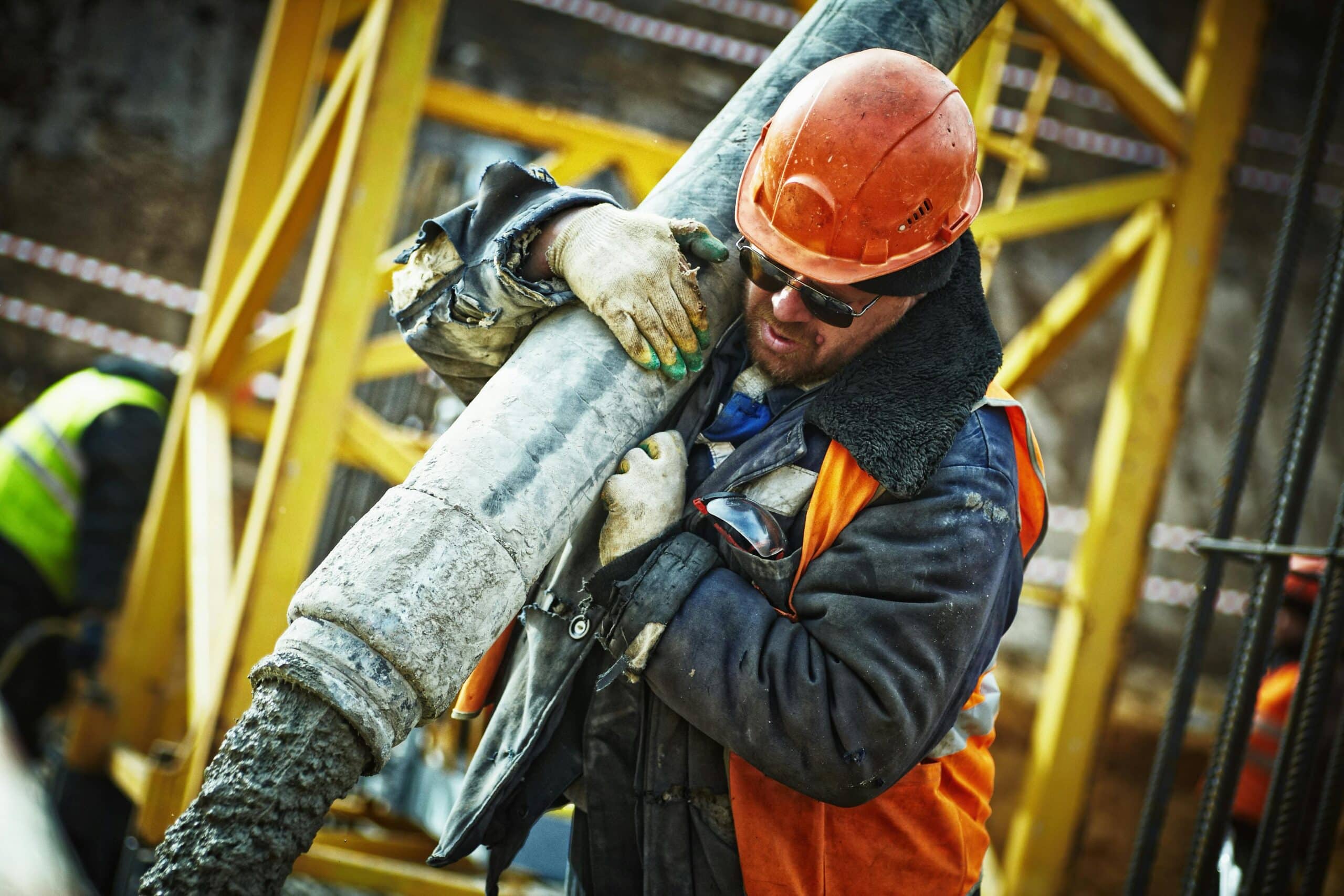 Construction worker in safety gear handling equipment on an active site.